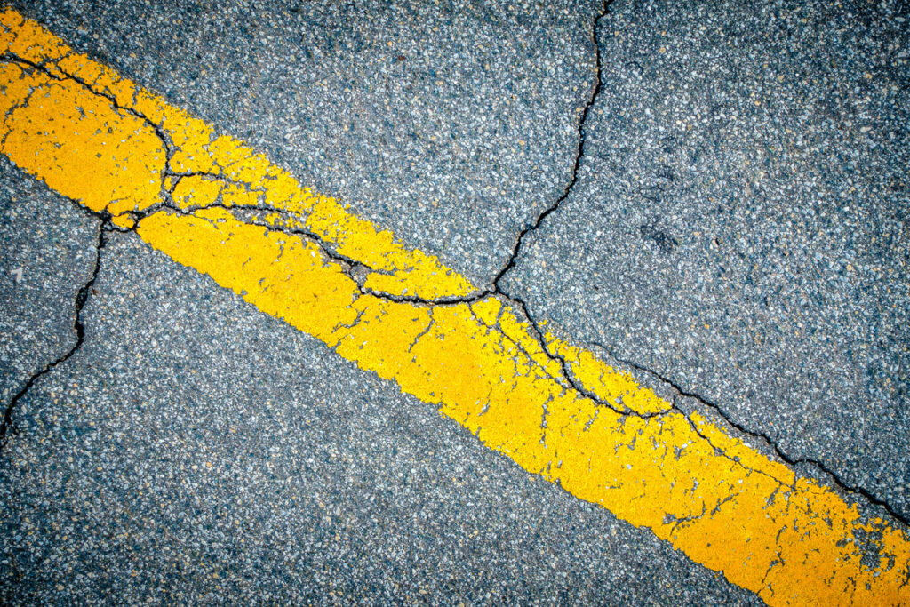 Cracked pavement with a yellow line through it in El Paso.